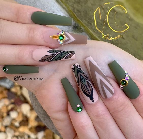 Green matte coffin-shaped nails with different patterns and gems 