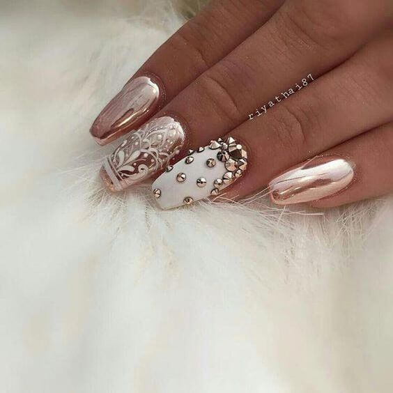 Gold studs on an accent nail on white nail polish